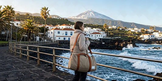 Voyageur avec un sac week-end sur une promenade de Tenerife sous le soleil d'hiver, le Teide enneigé au loin